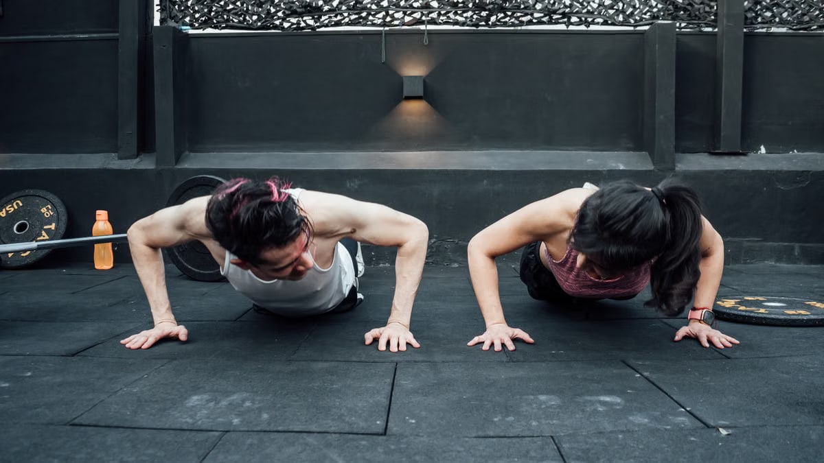 Two adults doing push-ups in an indoor gym setting in Mexico City, promoting a fit and healthy lifestyle.
